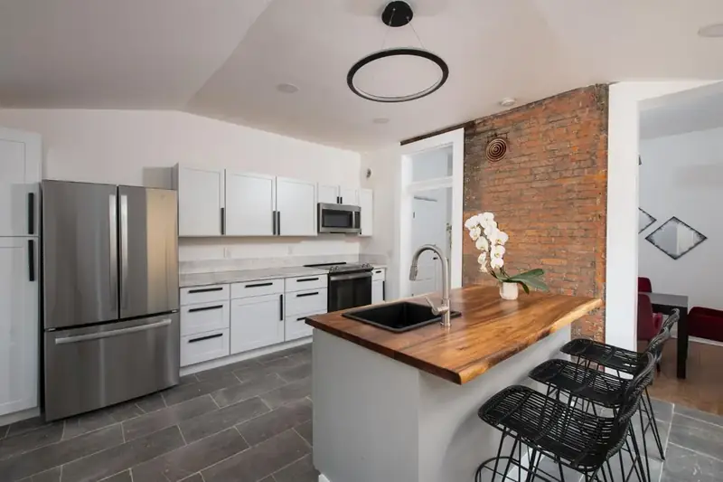 Kitchen with exposed brick wall and butcher-block island, 1880s Glam
