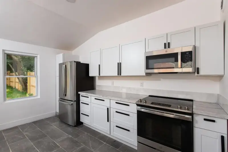 White kitchen with stainless appliances under a sloped ceiling, 1880s Glam