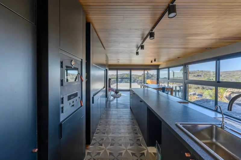 Galley kitchen with wood ceiling and window wall to the hills, Casa en Piedras