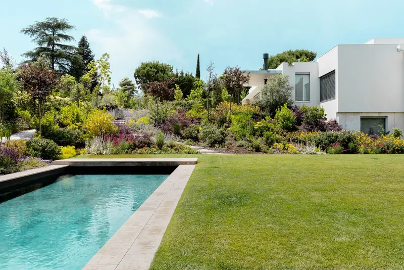 Lap pool and lawn bordered by flower beds, La Jungla