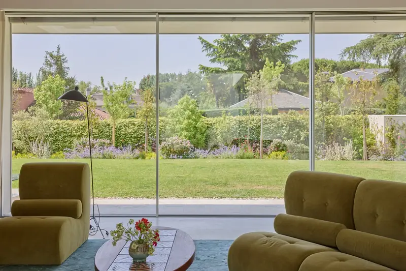 Living room with velvet sofas facing the garden through glass, La Jungla