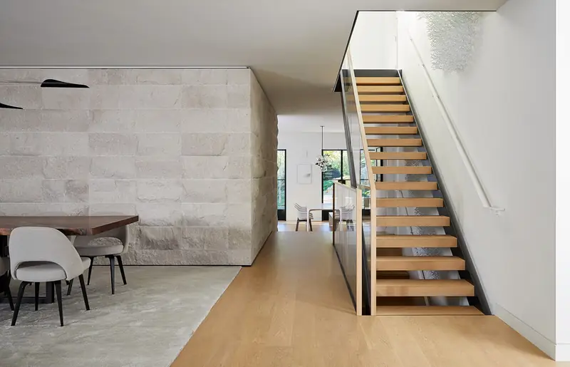 Floating wood staircase against a stone wall, Stone Haven